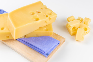 Fresh cheeses of different flavors with nuts on black chalkboard plate and wooden board on white commercial background and space for text