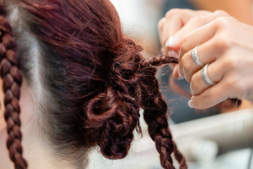 Fototapeta premium Details of the hairstyle of a young woman with braids, curls and flowers