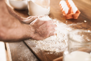 Cropped image of caucasian man in apron cooking dough