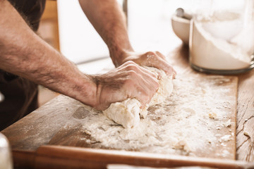 Cropped image of caucasian man in apron cooking dough
