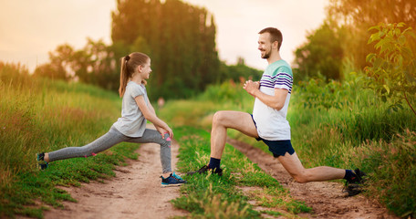 Athletic young father and little daughter do exercises in stadium.