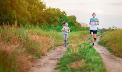 Obraz premium Father and daughter jogging. Cheerful father and daughter run in park together.