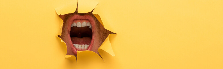 cropped view of open mouth in yellow paper hole