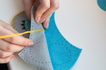 A girl sews an owl toy from felt. Cute stuffed toy is made manually. Easy sewing project for kids