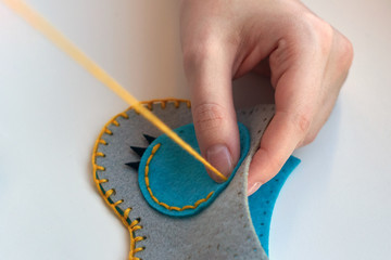 A girl sews an owl toy from felt. Cute stuffed toy is made manually. Easy sewing project for kids