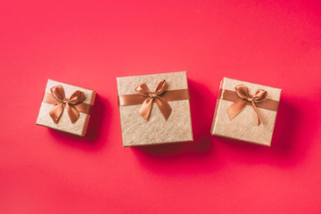 Gift box with sparkling gold glitter on pastel red background. Romantic card. New year, Christmas, Valentine's day concept of greetings. Copy text. Top view, flat lay.