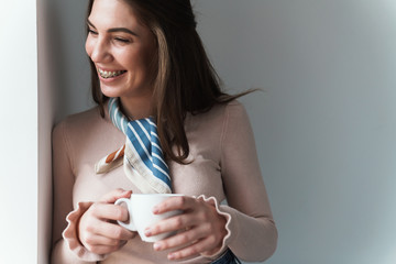 Positive young brunette woman drinking coffee.