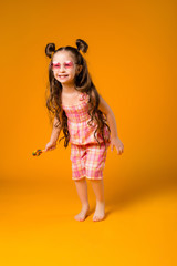 Adorable girl licking lollipop, on yellow background