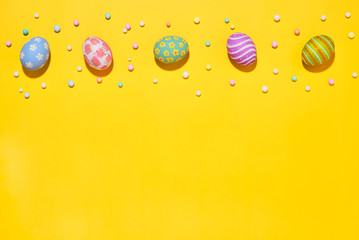 Creative Easter holiday layout eggs colored handmade paint ed with ribbon foam party on yellow background.Seasonal flat lay concept.
