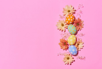 Creative Easter holiday layout eggs colored handmade paint ed with flower on pink background.Seasonal flat lay concept.