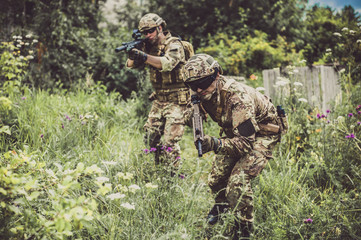 Two men in military camouflage vegetato uniforms with automatic assault rifles