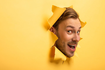 crazy handsome man with head in yellow paper hole - obrazy, fototapety, plakaty