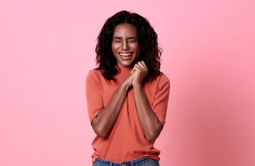 Happy smiling beautiful african woman looking at camera wearing orange t-shirt casual isolated on pink background.