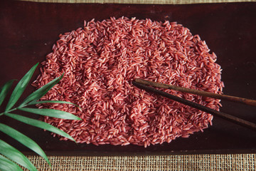 Red rice on wooden plate