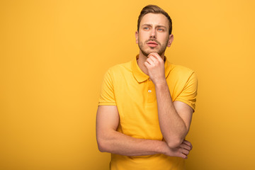 pensive handsome man in yellow outfit on yellow background