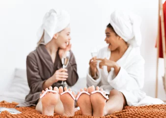 Foto auf Leinwand Freundinnen machen zu Hause Pediküre und trinken Champagner © Prostock-studio