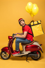 side view of delivery man looking at balloons on backpack on scooter on yellow background