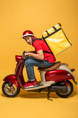 side view of delivery man with backpack on scooter on yellow background © LIGHTFIELD STUDIOS
