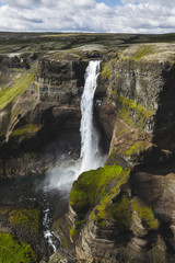Aerial view of Haifoss big waterfall in south Iceland. Black high rocks, green hills and nobody around. Sunny summer weather.