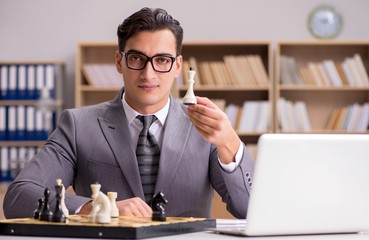 Young businessman playing chess in the office