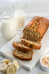 Banana bread with coconut and milk on a light gray background. Homemade delicious pastries. Side view, close- up, copy space.