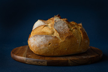 Round Bread Loaf or Boule on wood cutting board. Blue background. Rustic. Isolated. Concept: healthy live. 