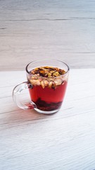 Fragrant fresh hot tea with fruits is poured into a glass mug on a light background. Tasty breakfast. Proper nutrition. Tea party.