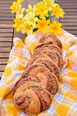 Babka. Chocolate Swirl Bread with Walnut and Cinnamon. Homemade sweet desert pastry. Yellow flowers at the background