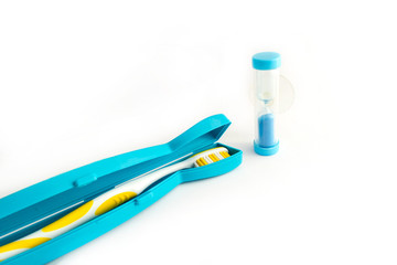 Toothbrush in a plastic case and dental Hourglass on white background