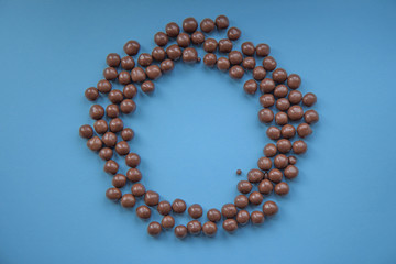 Chocolate balls on a blue background in the shape of a circle. Top view