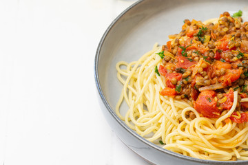 Tasty Spaghetti pasta served with tomato sauce, lentils, fresh tomatoes, pepper, paprika, persil in bowl on white table. Concept: vegan, vegetarian meal, healthy living. Copy space. Close up. 