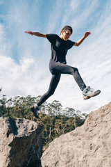 Young girl training for a mountain race. It is jumping between the rocks of the route. healthy...