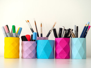 Colored pencil and pens holders decorating a white table