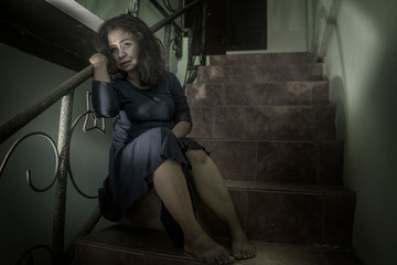 dramatic portrait of 50s woman depressed on staircase - mature lady sad and lonely suffering depression and middle age crisis sitting on stairs feeling abandoned and hopeless