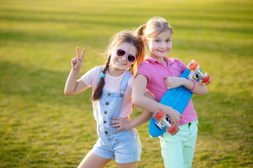 Portrait of two little happy kids with a skateboard. Doing outdoor sports in the park.