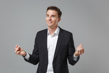 Successful young business man in classic suit shirt isolated on grey background. Achievement career wealth business concept. Mock up copy space. Rubbing fingers showing cash gesture asking for money.