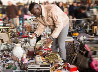 African American man chooses antiques on the flea market