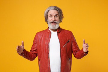 Shocked elderly gray-haired mustache bearded man in leather jacket isolated on yellow background. People lifestyle concept. Mock up copy space. Gesturing demonstrating size with horizontal workspace.