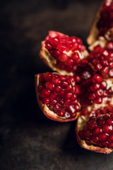 Broken red ripe pomegranate fruit on the dark rustic background. Selective focus. Shallow depth of field.