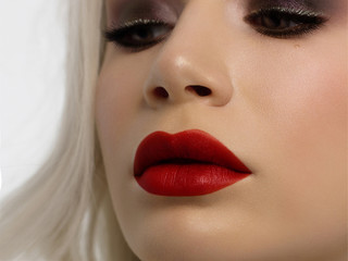 Naklejka premium Close-up portrait of the cleanliness face of a beautiful woman with dark burgundy smoky eyes makeup, red full lips. Sexy model with clean shiny skin, clean face, long curly hair. glamorous image