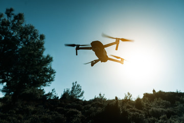 Fototapeta na wymiar A silhouette of a Quadrocopter drone with the camera against the blue sky.