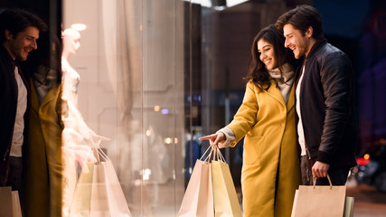 Woman showing something in mall window to her husband