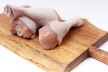 Raw uncooked chicken legs, drumsticks on wooden board