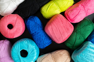 close up dark shadow background made of collection of colorful yarn rolls of natural material
