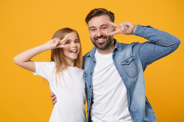 Obraz premium Cheerful bearded man in casual clothes have fun with cute child baby girl. Father little kid daughter isolated on yellow background. Love family day parenthood childhood concept. Showing victory sign.