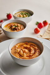 Close up view of plates and delicious hummus with chickpea and spices in bowls