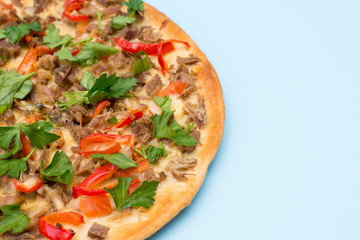 Tasty pizza with meat, pepper, cheese and greens on blue background with a copy space