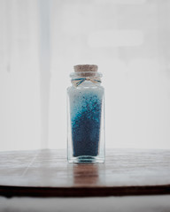 fancy bottle with blue bath salts for relaxing spa treatments with white background