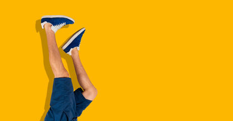 the simple human legs in sneakers upside down against the colorful wall, trendy chill and relax concept wide webn banner