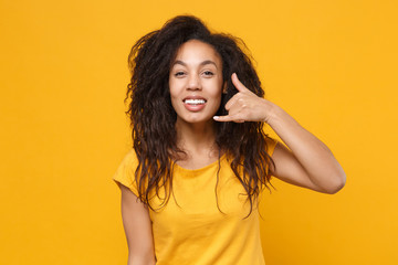 Funny young african american woman girl in casual t-shirt posing isolated on yellow orange background in studio. People lifestyle concept. Mock up copy space. Doing phone gesture says call me back.